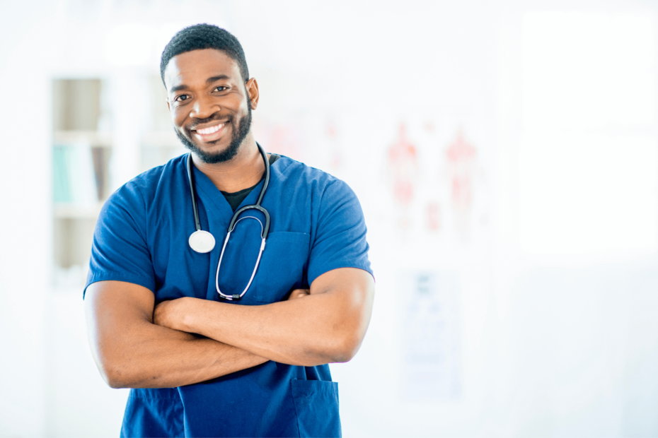 A nurse in scrubs with a stethoscope, standing with his arms crossed.