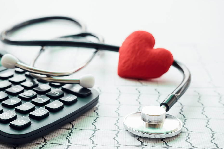 A stethoscope and a calculator with a plush heart resting on them.