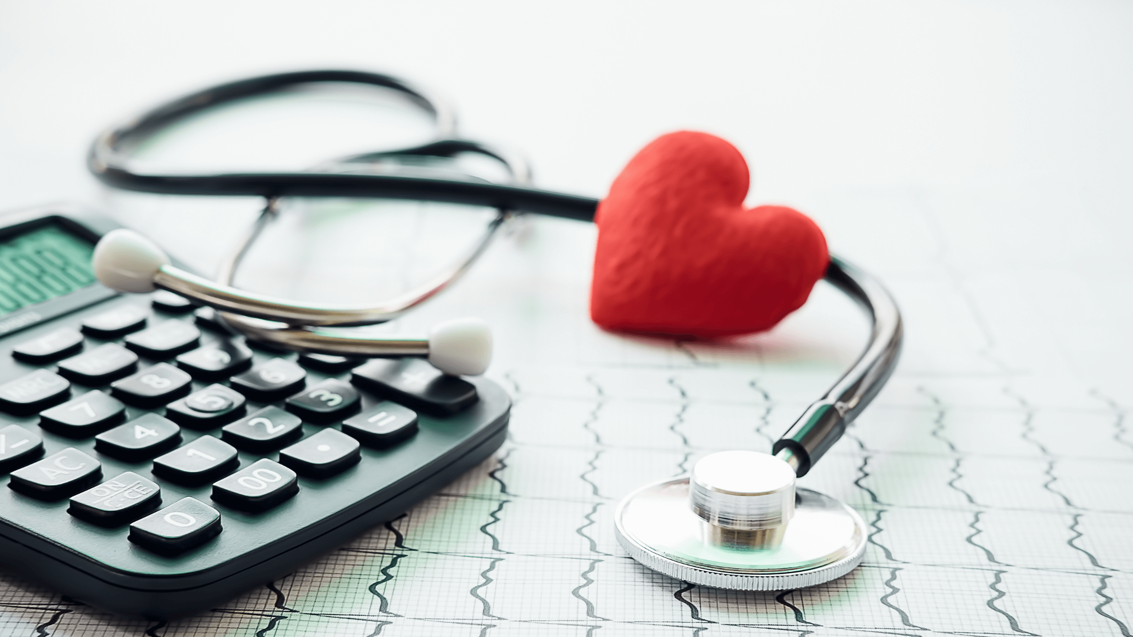 A stethoscope and a calculator with a plush heart resting on them.