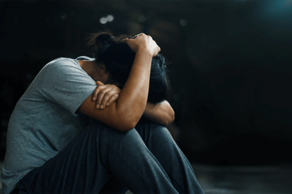 A person with their hands on their head and their head on their knees.