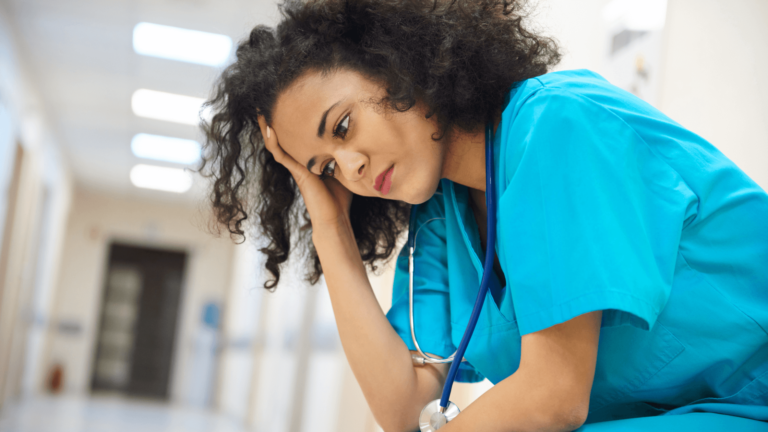 A nurse with her head resting on her hand.