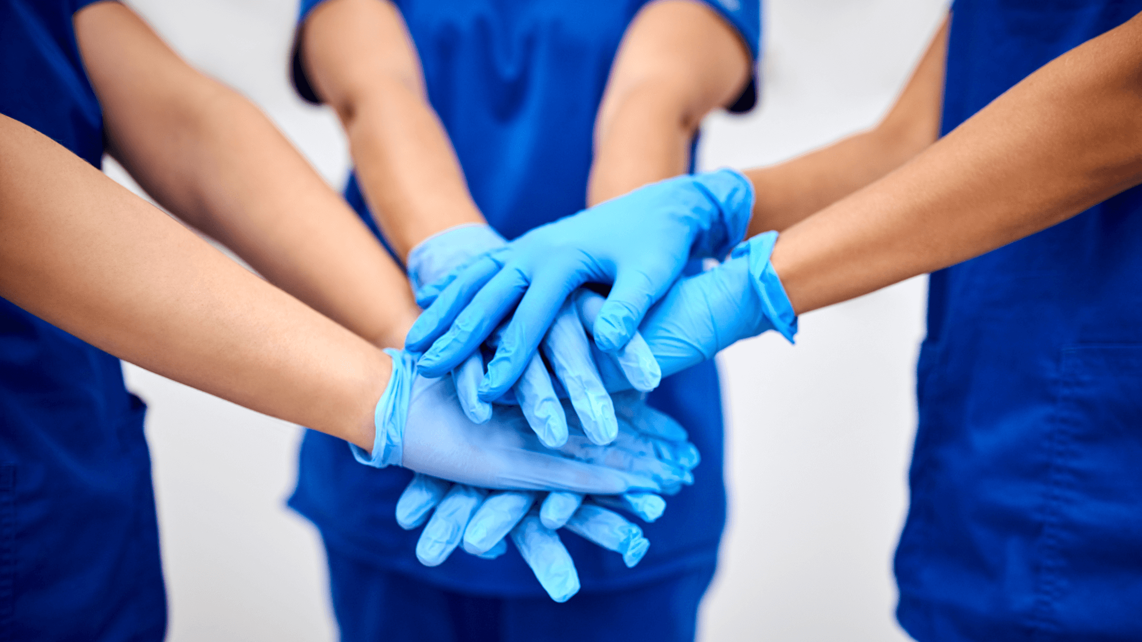 A close-up of a group of hands with surgical glovers on them.