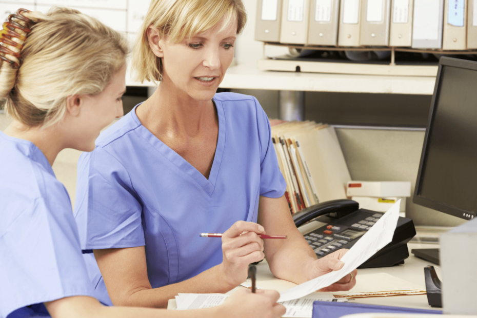 Two nurses talking while reviewing a document.