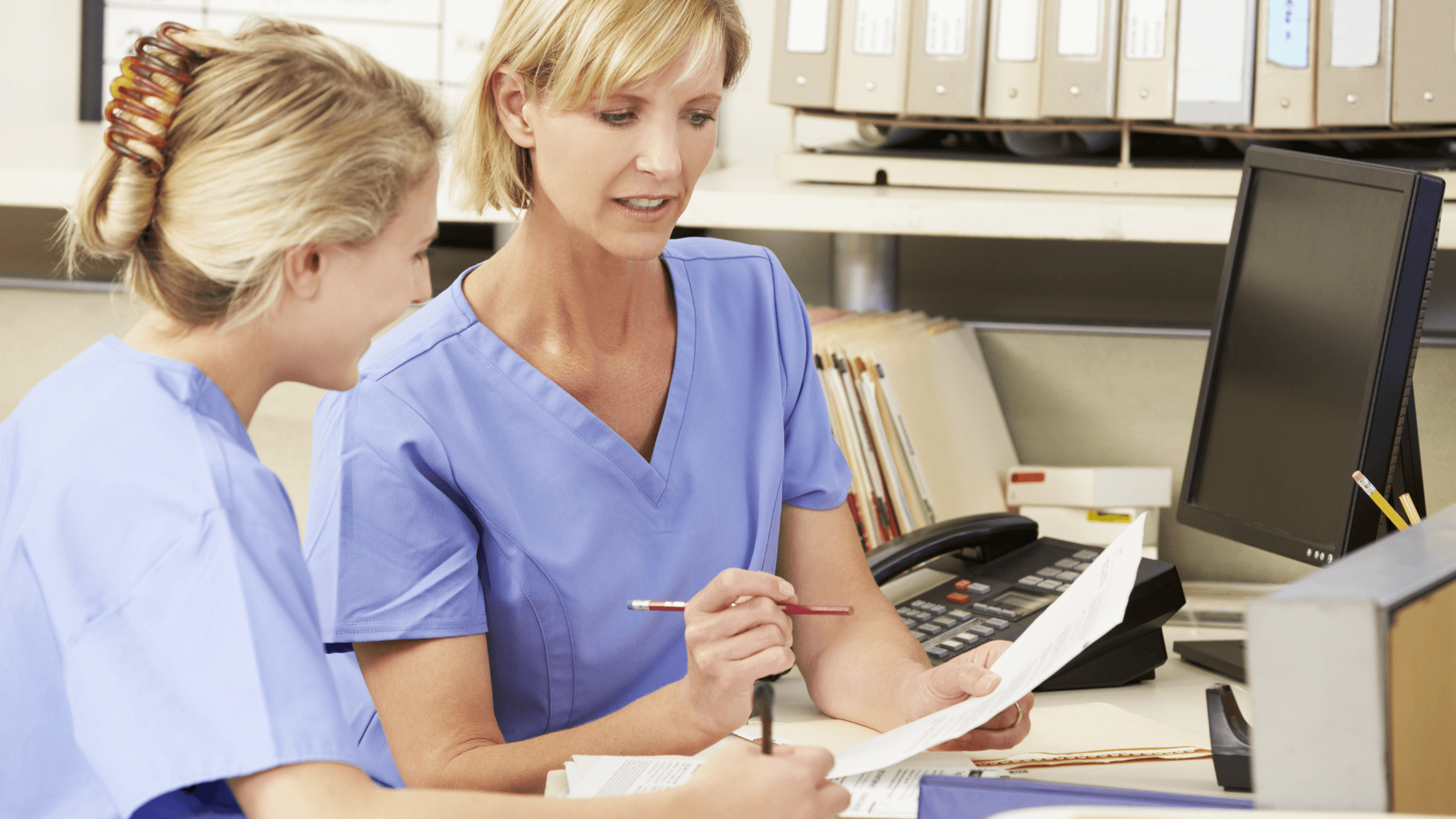 Two nurses talking while reviewing a document.