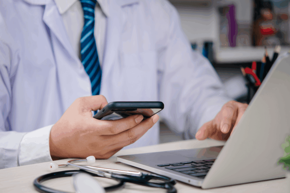 Close up of a doctor looking at a laptop and cell phone