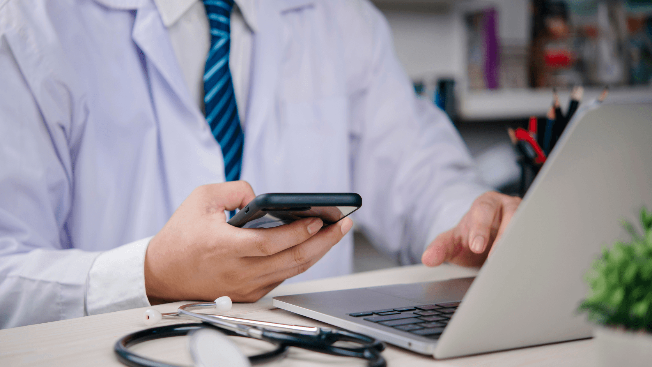 Close up of a doctor looking at a laptop and cell phone