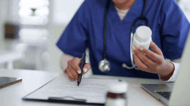 A nurse looking at a clipboard while holding a bottle of medication